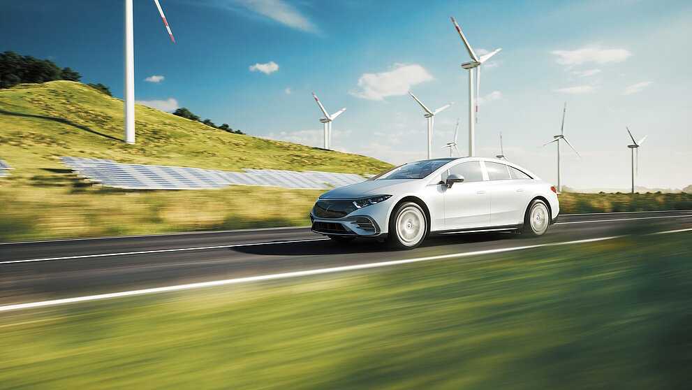 Electric sports car drives past solar panels and wind turbines